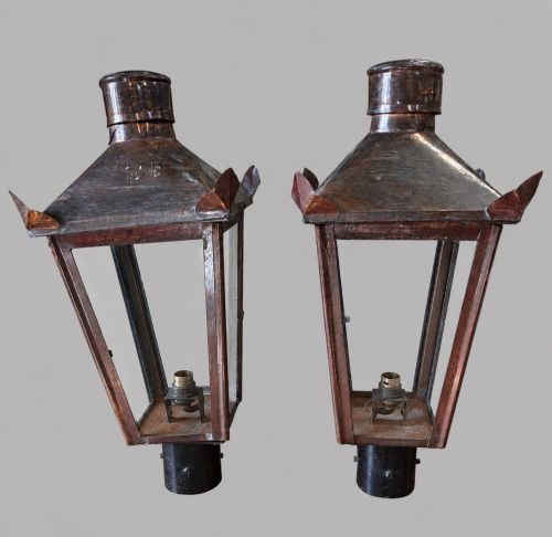 fig 1. A pair of tapered copper post lanterns featuring clear glass side panels, cylindrical top chimneys, corner fins, and black collar mounts.