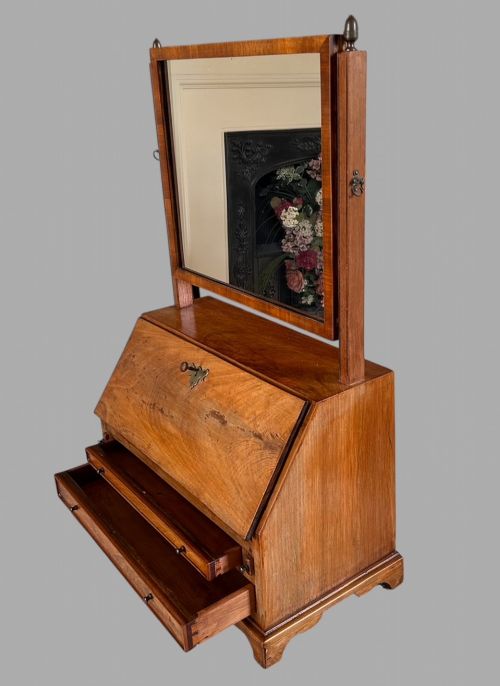 fig 3. An Edwardian satinwood tabletop bureau featuring a slant-front writing slope over small drawers, topped with a rectangular swivel dressing mirror.