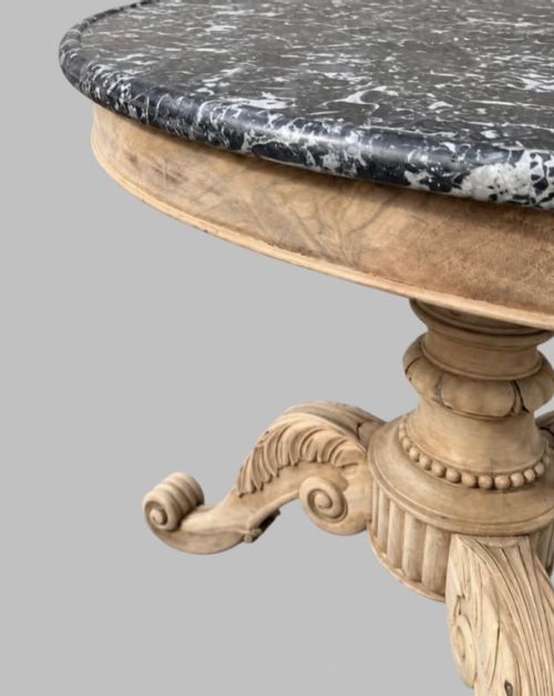 fig 3. A circular antique French gueridon table featuring a dark grey mottled marble top supported by a carved bleached walnut pedestal and tripod scrolled legs.