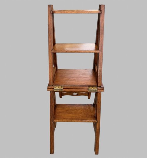 fig 1. An Arts and Crafts style warm brown oak metamorphic library chair featuring a pierced heart-shaped cutout on the top rail and a hinged seat mechanism.
