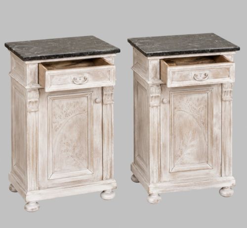 fig 1. A matching pair of mid-nineteenth-century off-white painted wooden bedside cabinets featuring dark marble tops, single drawers, fluted side pilasters, carved floral door panels, and turned bun feet.