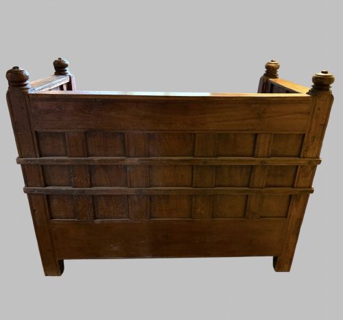 fig 3. A carved dark hardwood storage bench with a hinged lid seat, geometric panelled backrest, corner post finials, and iron fittings.