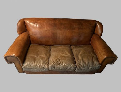 fig 1. A three-seater Art Deco sofa upholstered in warm brown patinated leather with metal studding along the armrests.