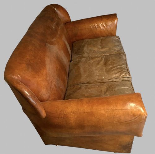 fig 4. A three-seater Art Deco sofa upholstered in warm brown patinated leather with metal studding along the armrests.
