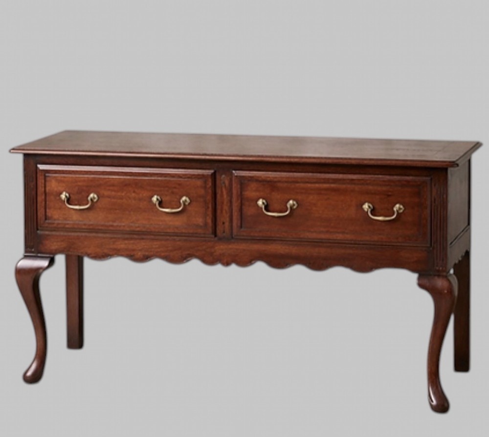 A late nineteenth-century oak dresser base featuring two drawers with brass handles, a scalloped lower apron, and cabriole legs.