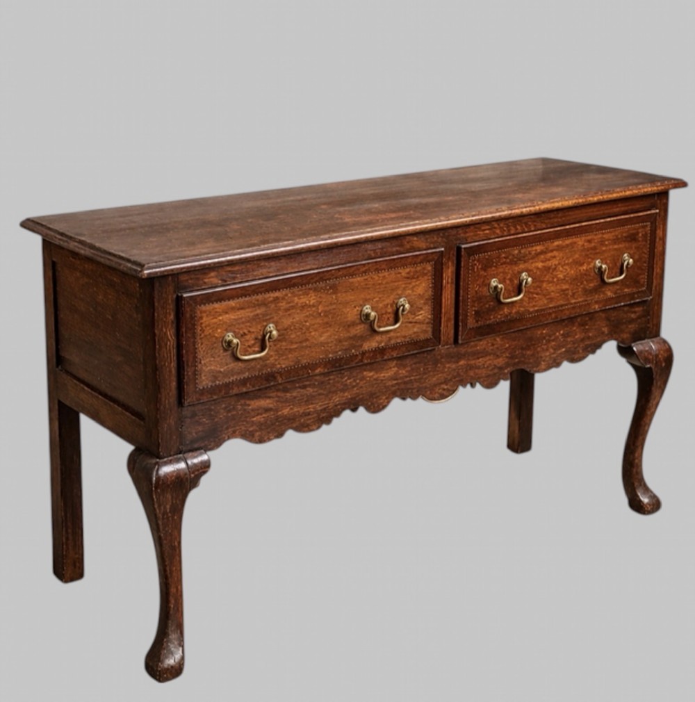 A late nineteenth-century oak dresser base featuring two drawers with brass handles, a scalloped lower apron, and cabriole legs. View II