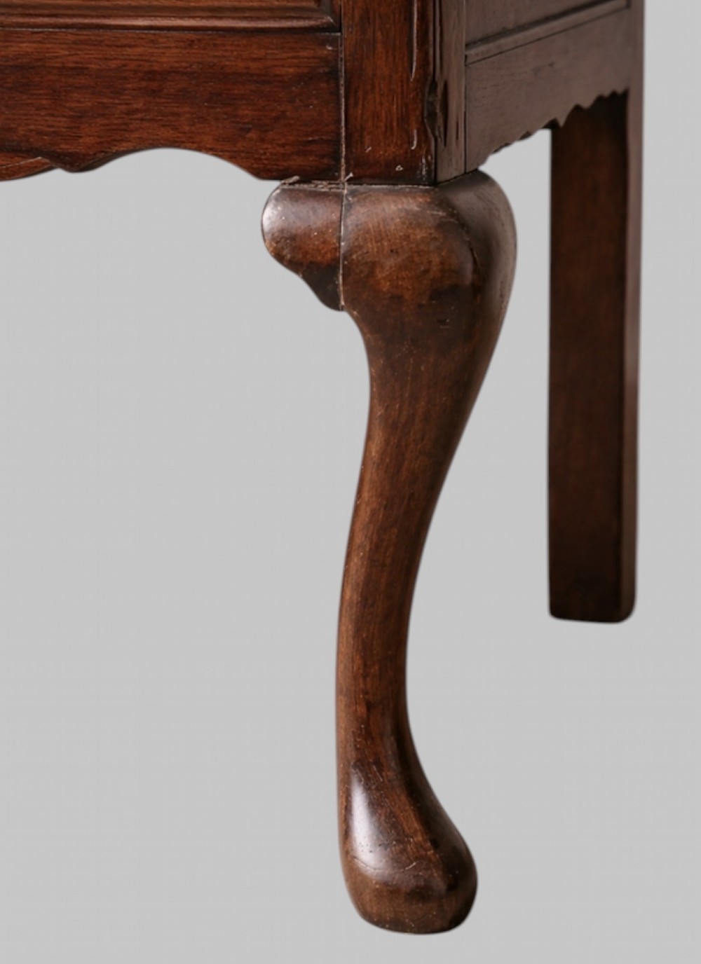 A late nineteenth-century oak dresser base featuring two drawers with brass handles, a scalloped lower apron, and cabriole legs. View V