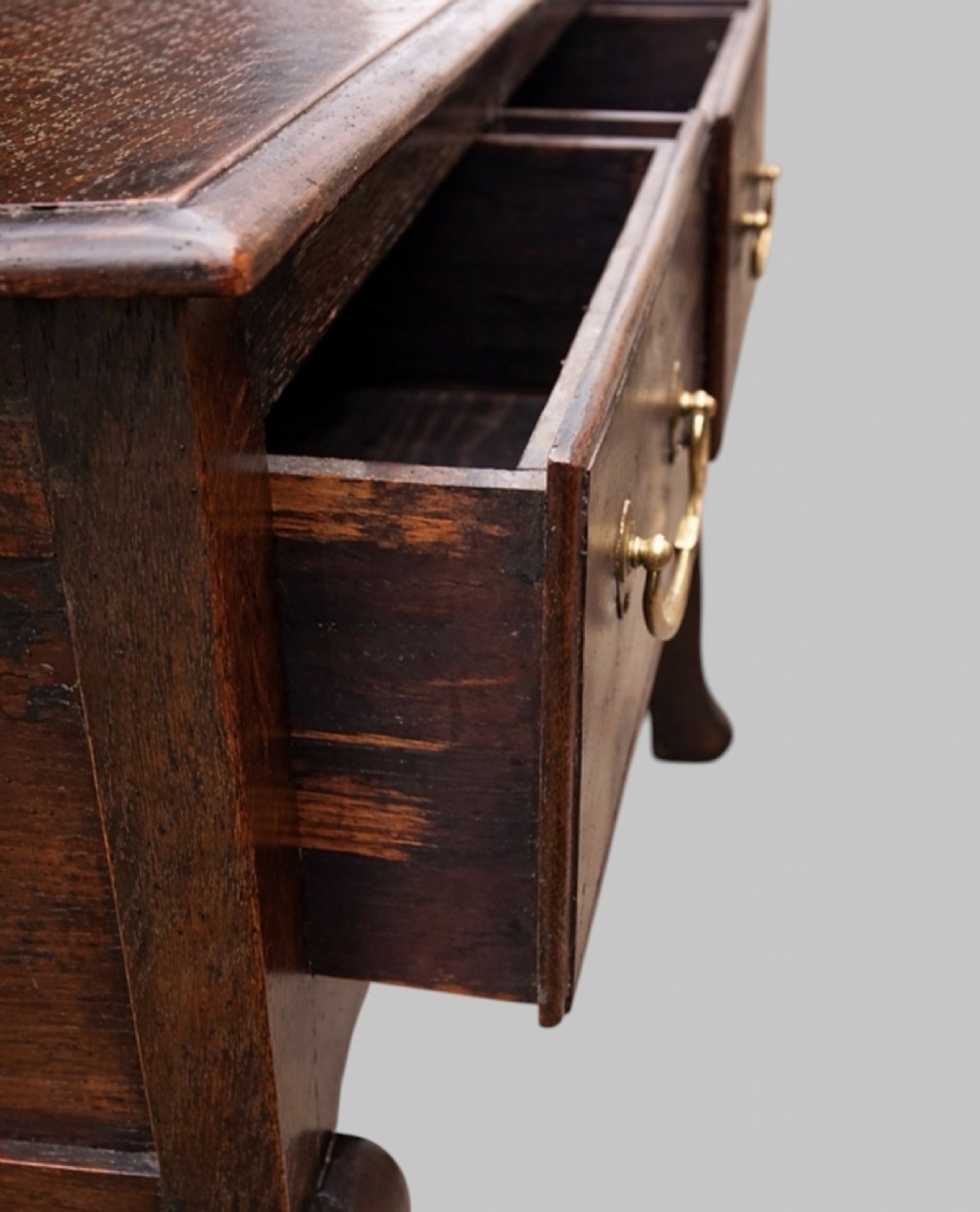 A late nineteenth-century oak dresser base featuring two drawers with brass handles, a scalloped lower apron, and cabriole legs. View VII