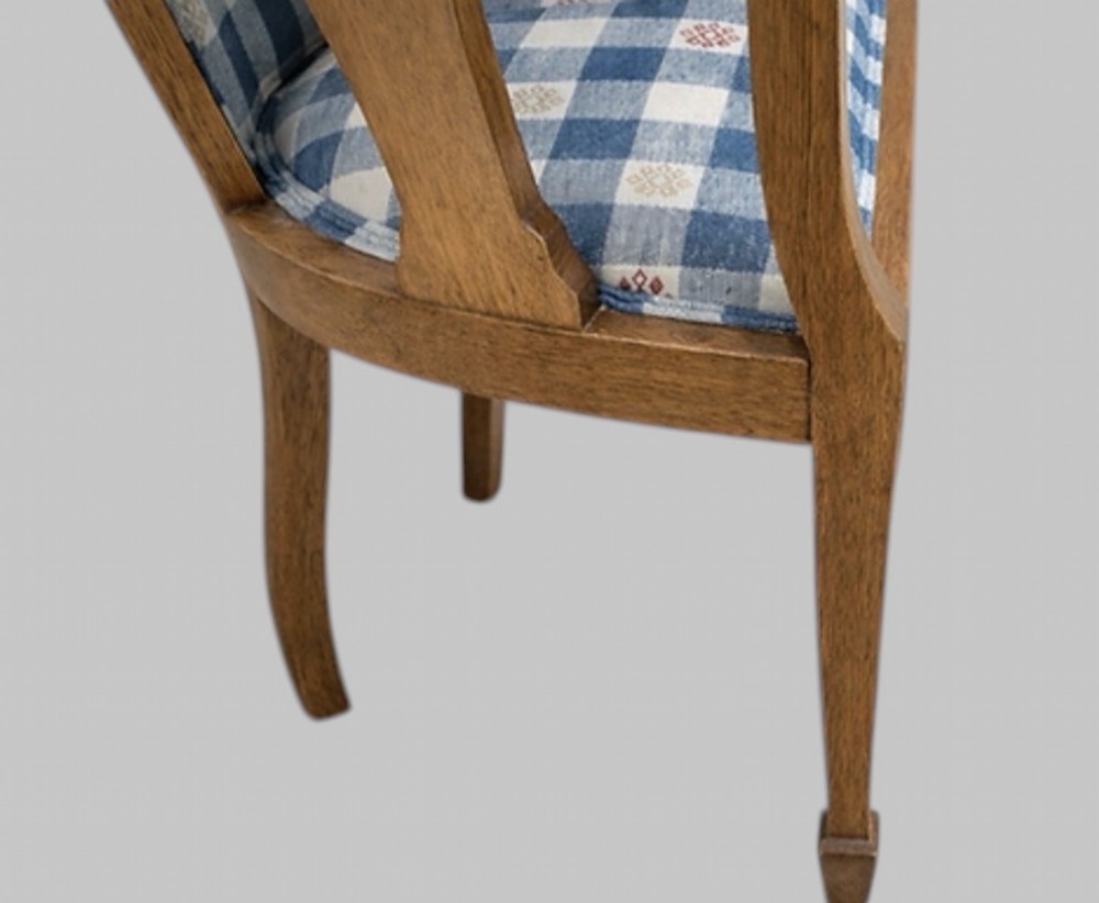 A pair of Arts and Crafts oak tub armchairs with curved wooden frames and blue and white checked fabric upholstery. View III
