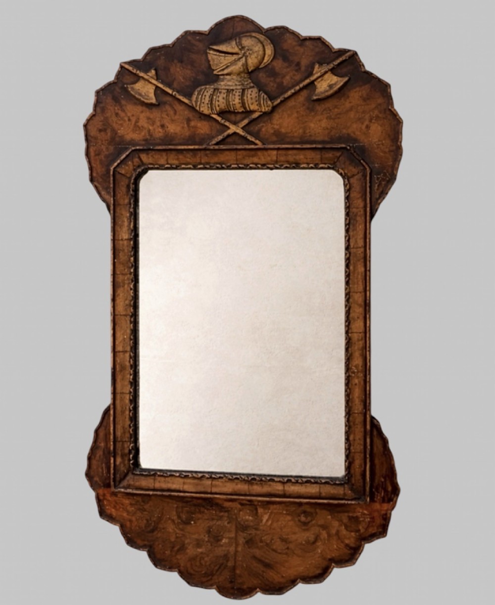 A late nineteenth-century carved walnut wall mirror featuring a scalloped outline, a central rectangular mirror frame, and an armorial crest detailing a knight helmet above crossed battleaxes.