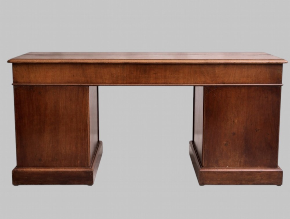 A late Victorian mahogany pedestal desk featuring an inset red leather writing surface, nine drawers with round brass pulls, and two plinth bases. View II