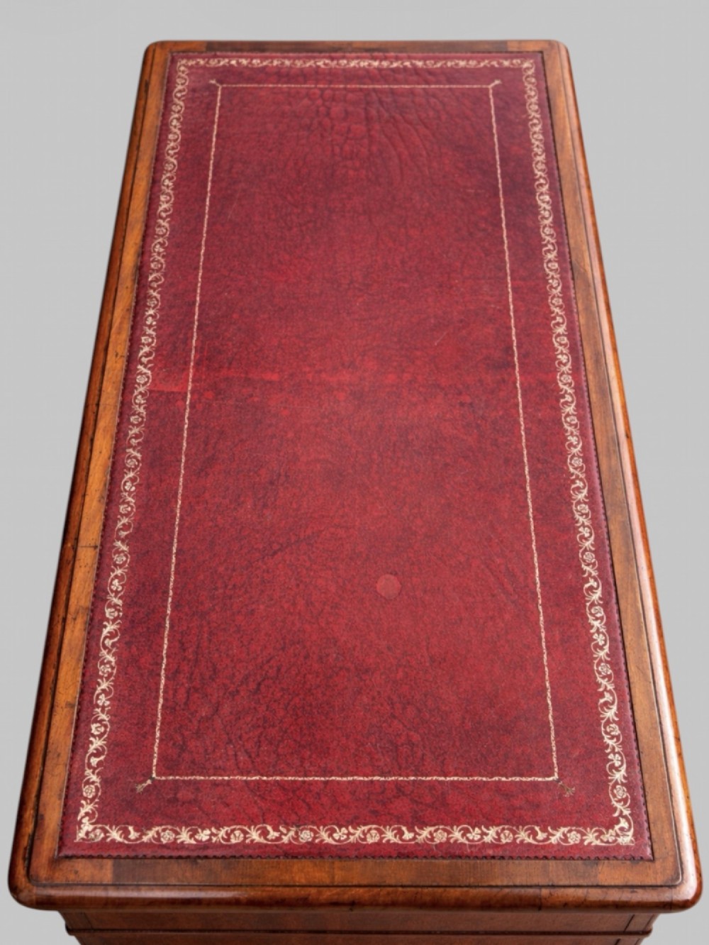 A late Victorian mahogany pedestal desk featuring an inset red leather writing surface, nine drawers with round brass pulls, and two plinth bases. View III