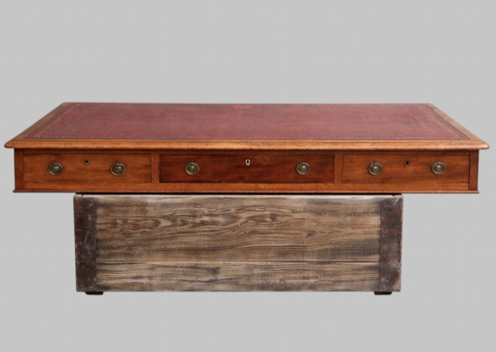 A late Victorian mahogany pedestal desk featuring an inset red leather writing surface, nine drawers with round brass pulls, and two plinth bases. View IV