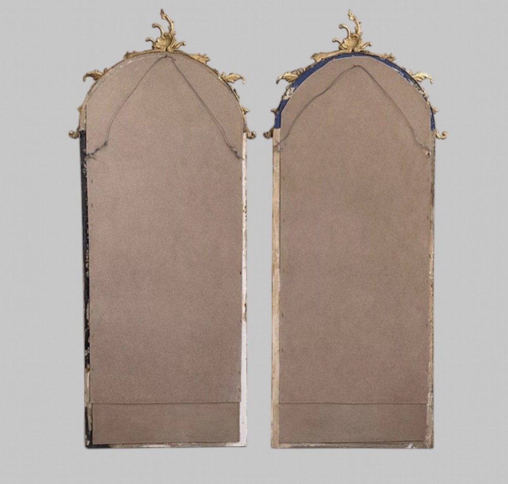 A pair of tall arched giltwood mirrors featuring detailed acanthus leaf cresting and moulded gold frames. View V
