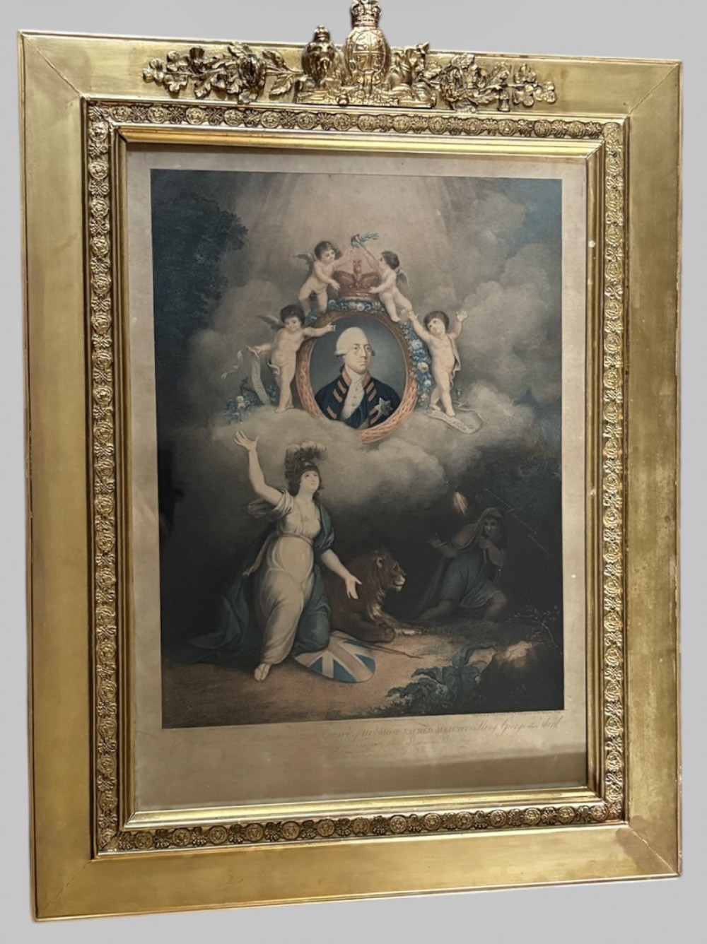 A framed 1802 Late-Georgian allegorical print depicting King George III surrounded by cherubs and classical figures within a carved gilt frame.