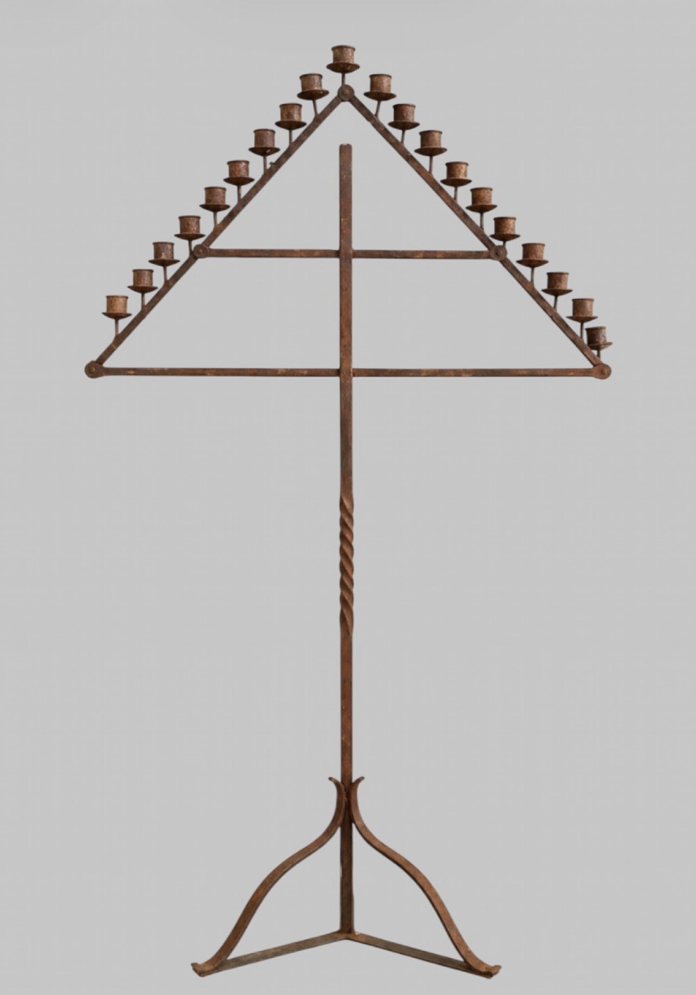 A tall dark wrought iron floor candelabrum featuring a triangular frame with fifteen candle sockets set upon a twisted central stem and tripod base.