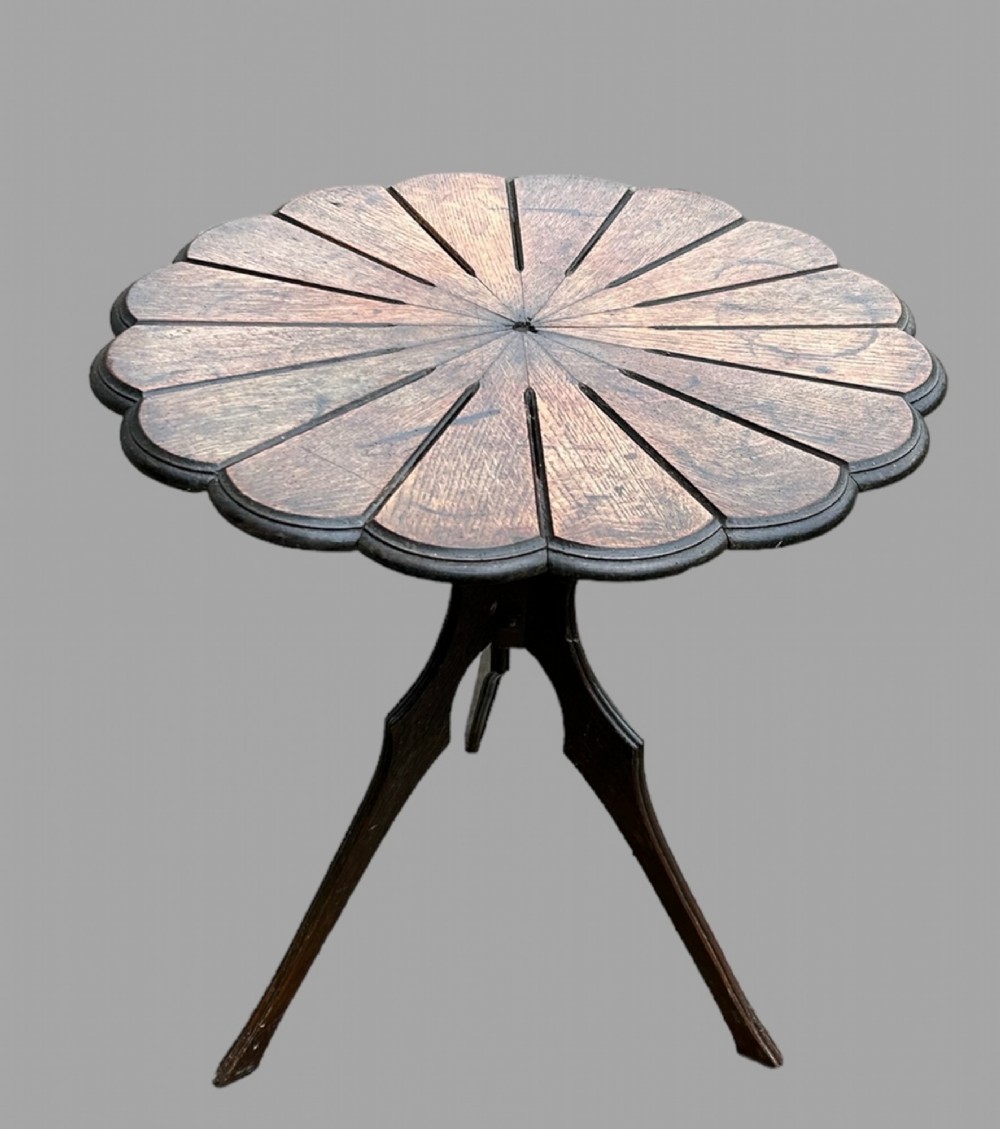 A seven-piece dark carved oak parlour suite comprising a central round table, five chairs, and one stool with radiating petal design tops and curved trestle legs. View IV