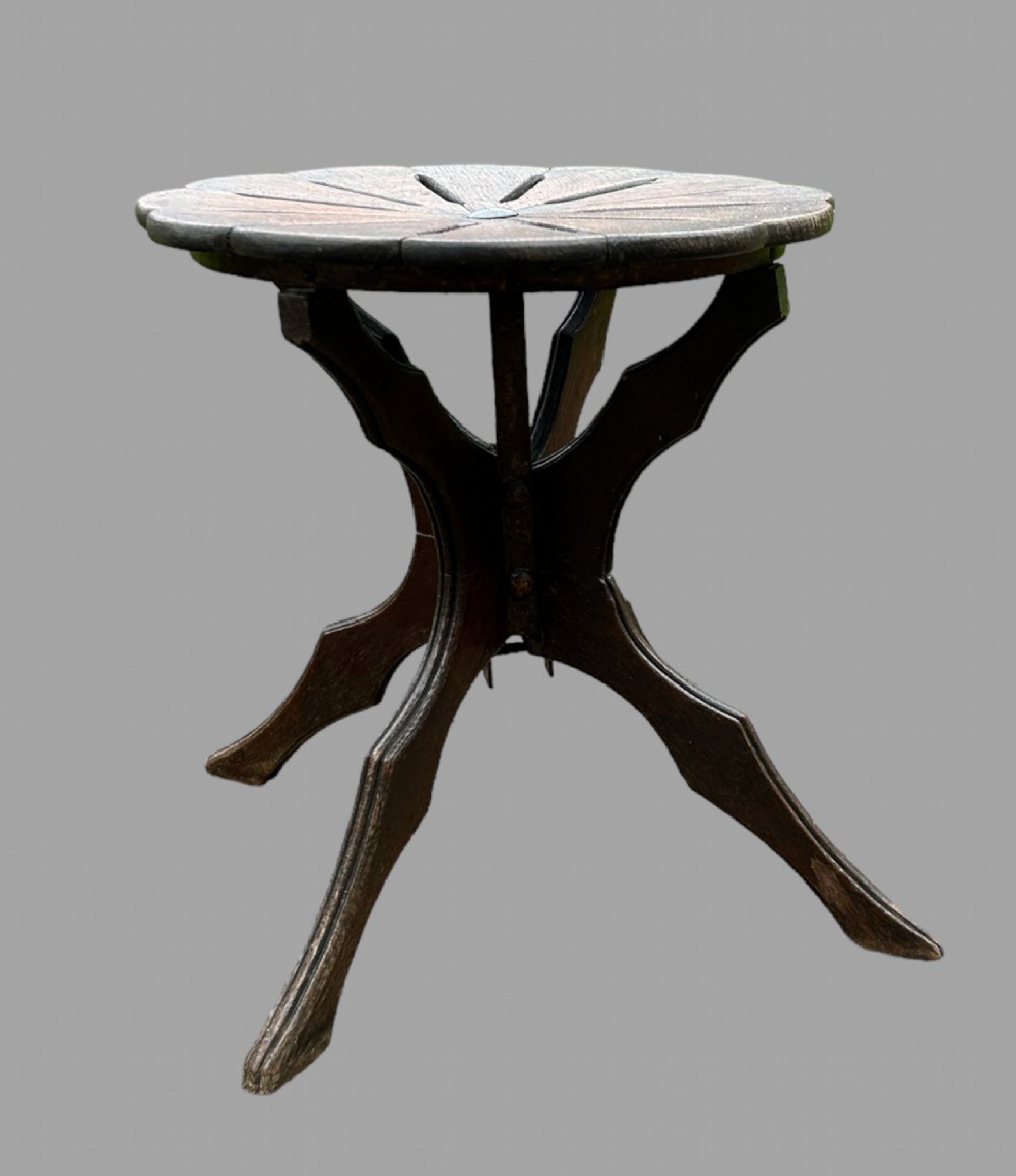 A seven-piece dark carved oak parlour suite comprising a central round table, five chairs, and one stool with radiating petal design tops and curved trestle legs. View V