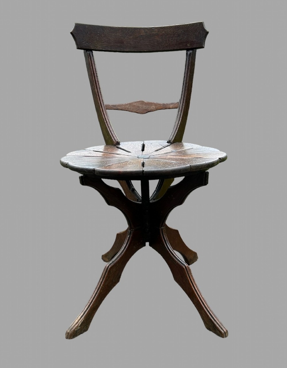 A seven-piece dark carved oak parlour suite comprising a central round table, five chairs, and one stool with radiating petal design tops and curved trestle legs. View VII