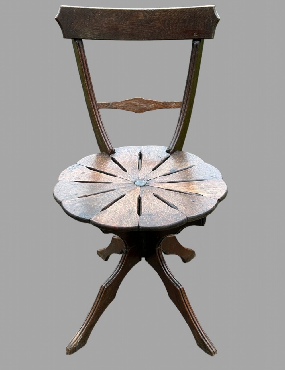 A seven-piece dark carved oak parlour suite comprising a central round table, five chairs, and one stool with radiating petal design tops and curved trestle legs. View VIII