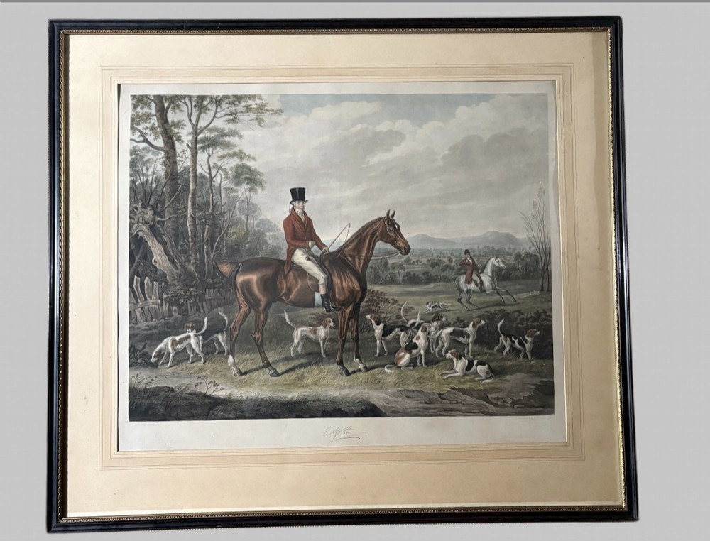 A Regency hand-coloured aquatint print depicting a horse rider in hunting attire with foxhounds in an open rural landscape. View II