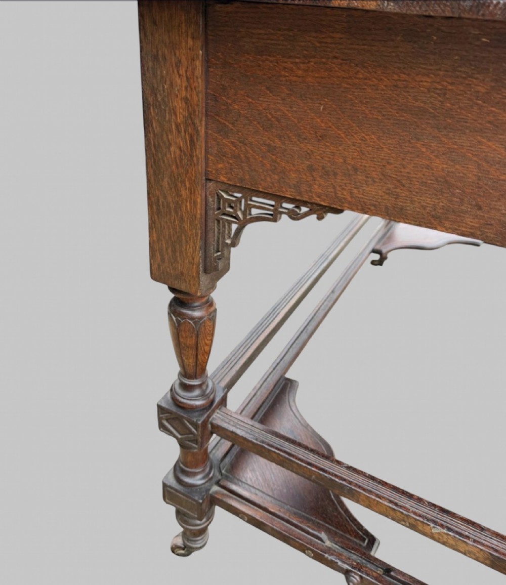 Victorian carved oak writing desk featuring a leather inset surface, two raised drawer cabinets on the top, two carved frieze drawers with brass drop handles, turned legs, and stretchers. View IX