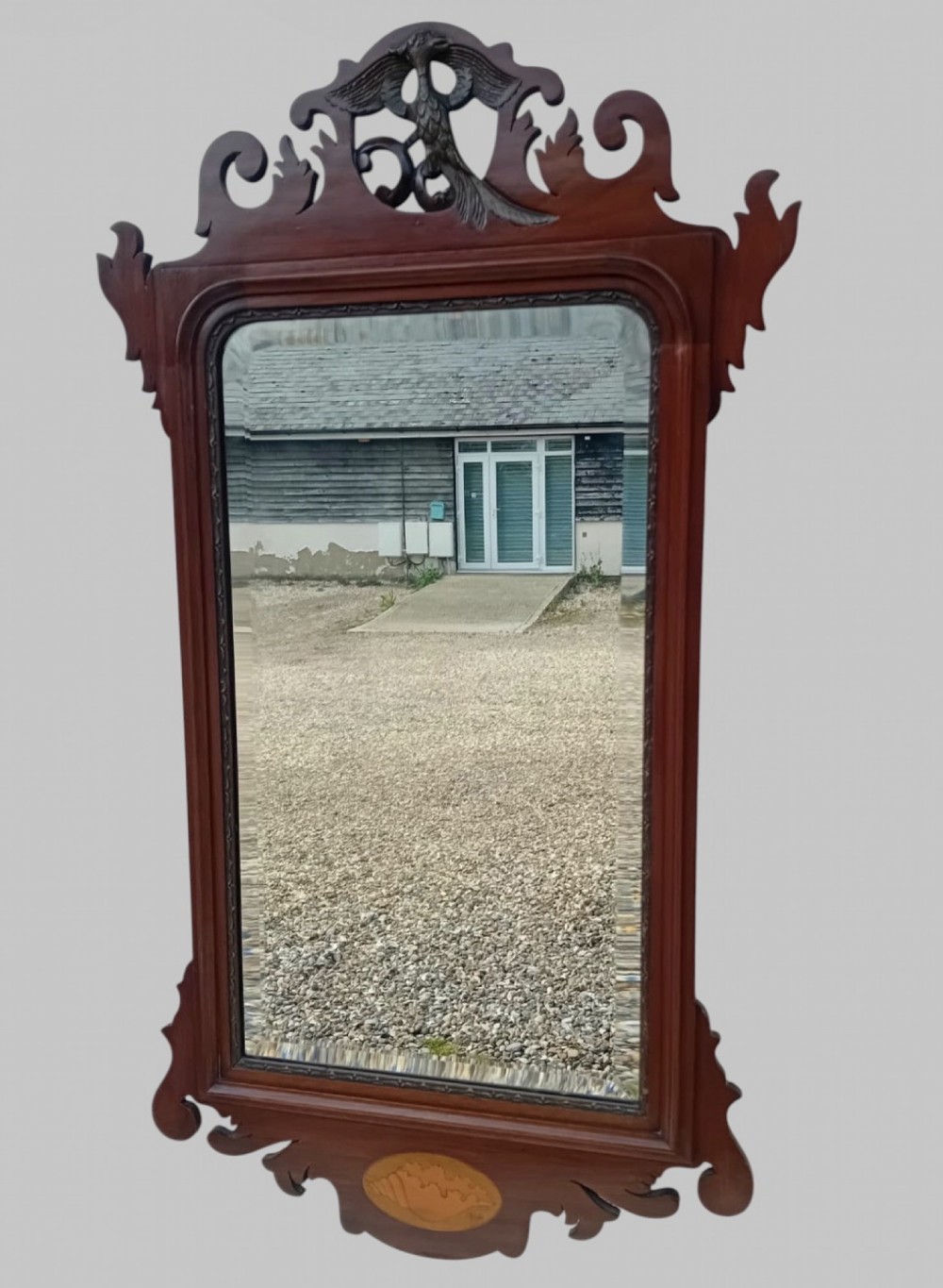 A tall Victorian Chippendale Revival mahogany wall mirror with a scrollwork fretcut frame, a crest depicting a bird, an oval shell inlay at the base, and bevelled glass. View II