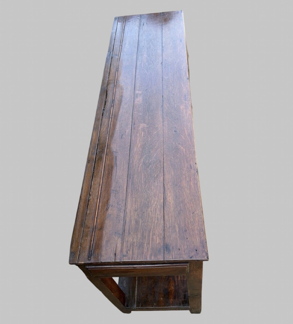 An 18th-century Welsh oak potboard dresser base featuring three frieze drawers with brass handles, a shaped apron, and a lower shelf. View II