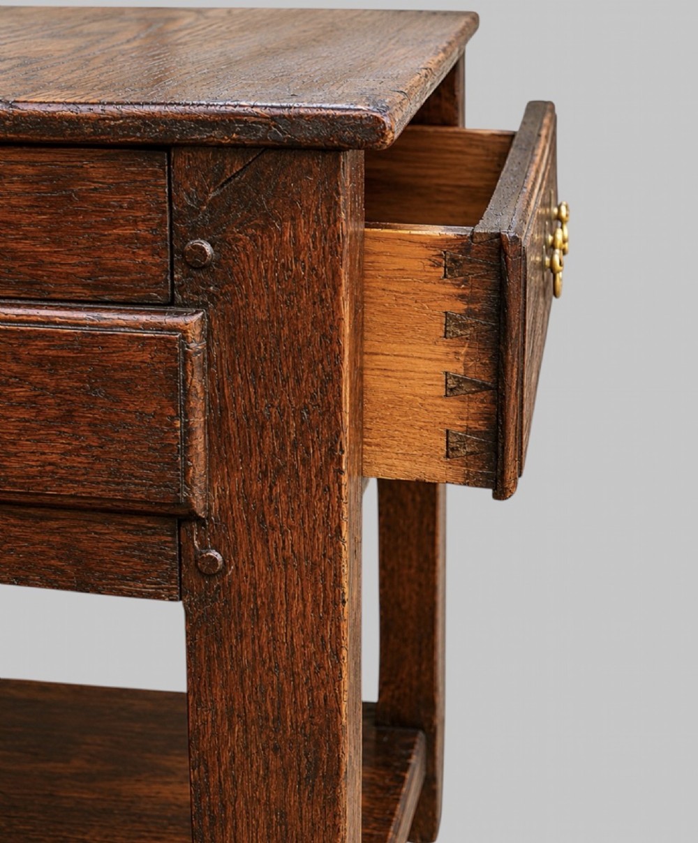 An 18th-century Welsh oak potboard dresser base featuring three frieze drawers with brass handles, a shaped apron, and a lower shelf. View VII