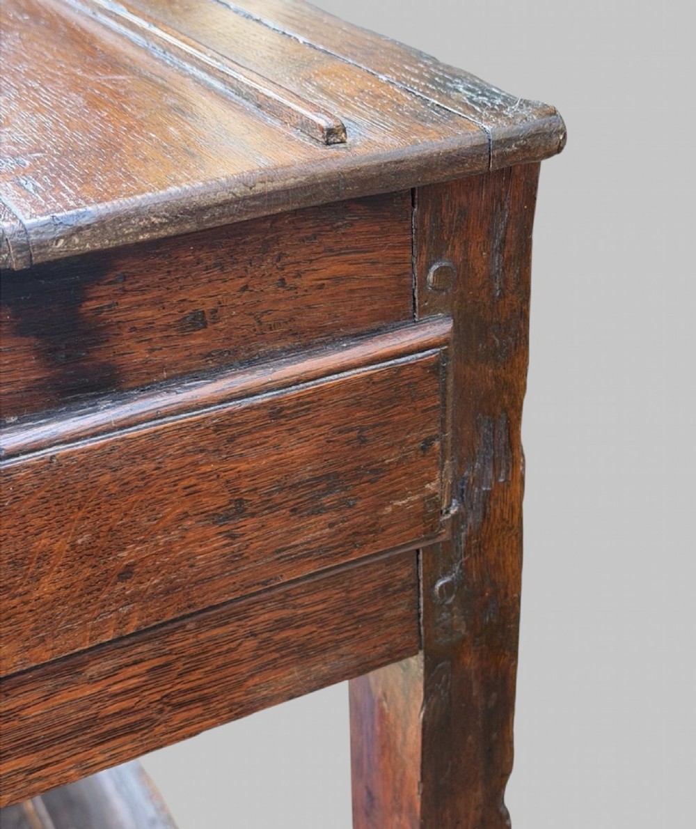 An 18th-century Welsh oak potboard dresser base featuring three frieze drawers with brass handles, a shaped apron, and a lower shelf. View IX