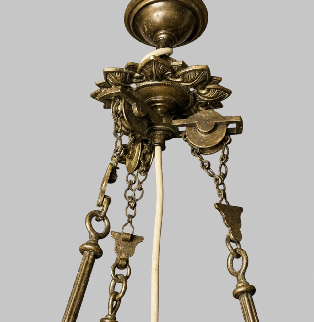 A late Victorian brass hanging lamp featuring a white opaline glass shade, decorative rams head side scrolls, and a central burner unit. View V