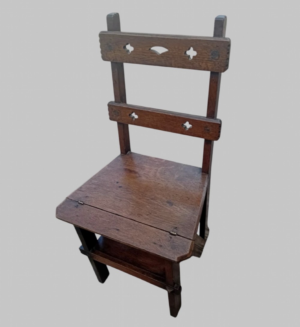 A late Victorian dark oak metamorphic chair featuring pierced trefoil cutouts on the backrest that hinges open to transform into a set of three library steps. View II