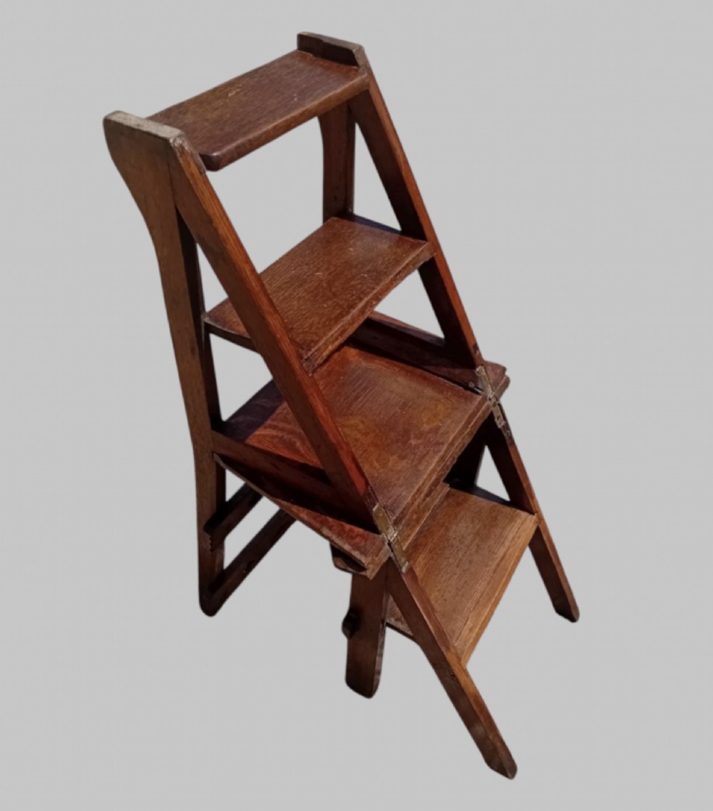 A late Victorian dark oak metamorphic chair featuring pierced trefoil cutouts on the backrest that hinges open to transform into a set of three library steps. View III