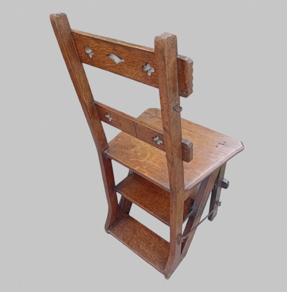 A late Victorian dark oak metamorphic chair featuring pierced trefoil cutouts on the backrest that hinges open to transform into a set of three library steps. View IV