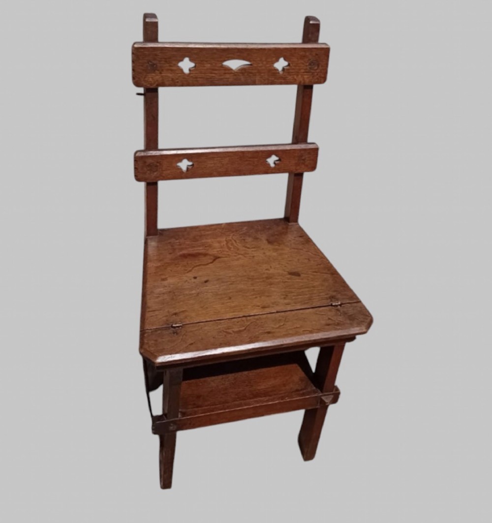 A late Victorian dark oak metamorphic chair featuring pierced trefoil cutouts on the backrest that hinges open to transform into a set of three library steps. View VI
