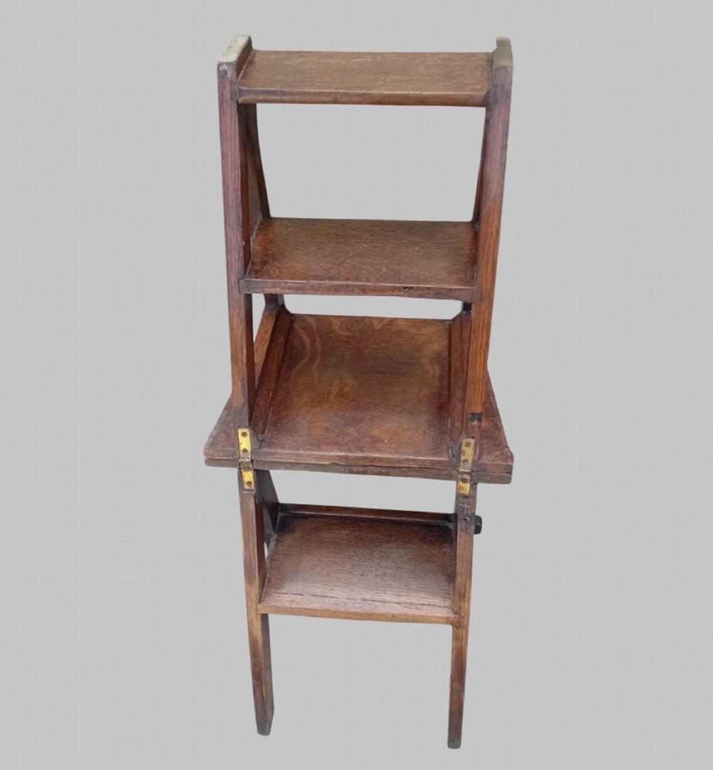 A late Victorian dark oak metamorphic chair featuring pierced trefoil cutouts on the backrest that hinges open to transform into a set of three library steps. View VII