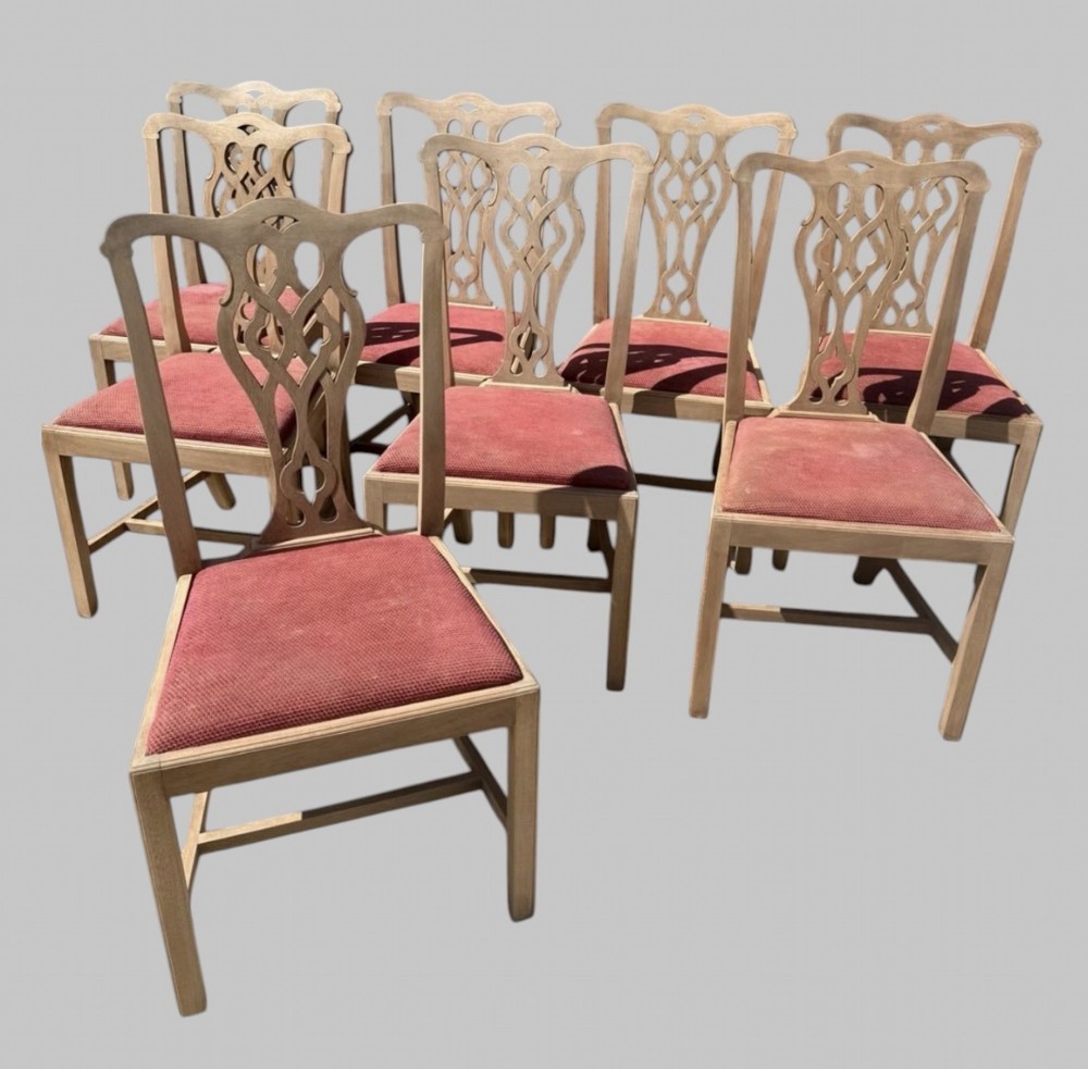 A set of eight bleached mahogany Georgian dining chairs featuring pierced fretwork back splats, straight square legs, and red fabric upholstered seats.