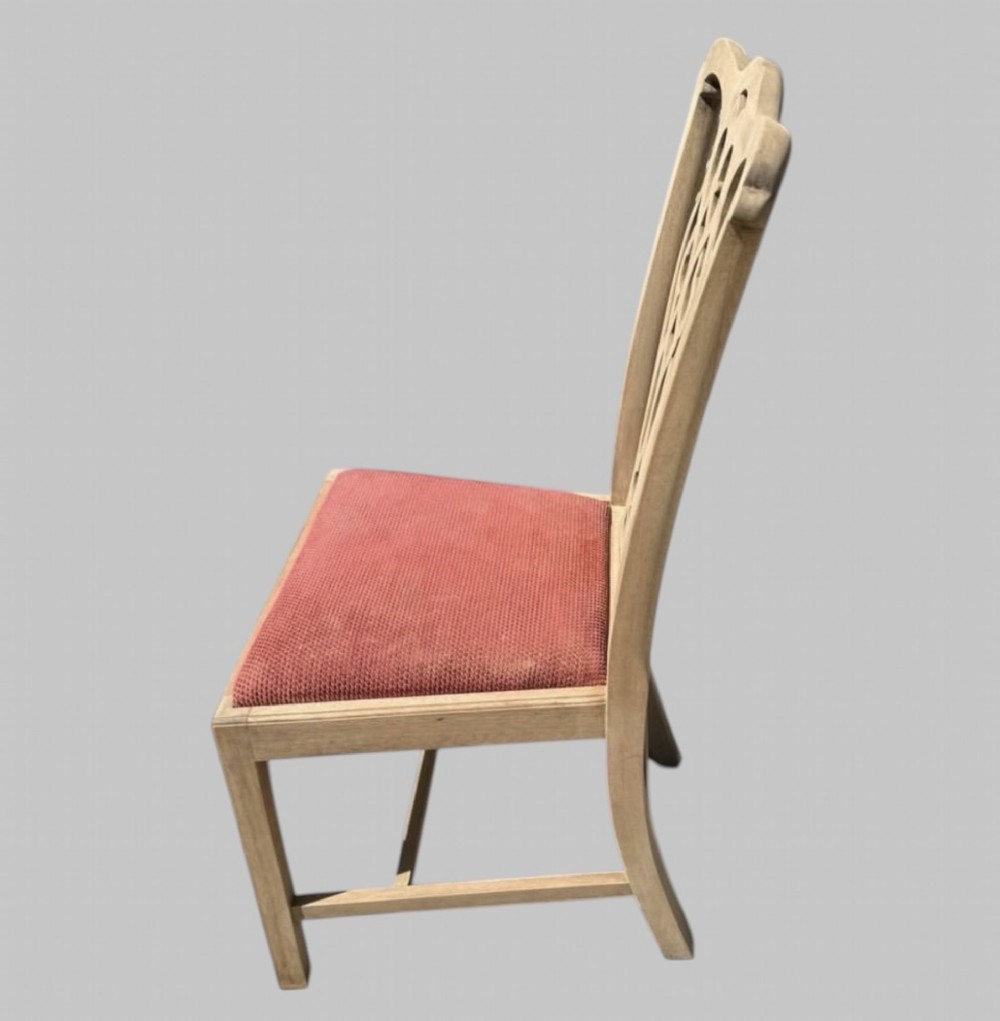 A set of eight bleached mahogany Georgian dining chairs featuring pierced fretwork back splats, straight square legs, and red fabric upholstered seats. View V