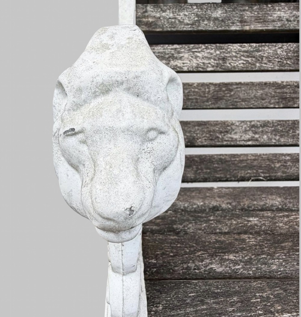 A pair of cast iron garden armchairs featuring white painted frames with lion mask armrest terminals and weathered timber slats. View VII