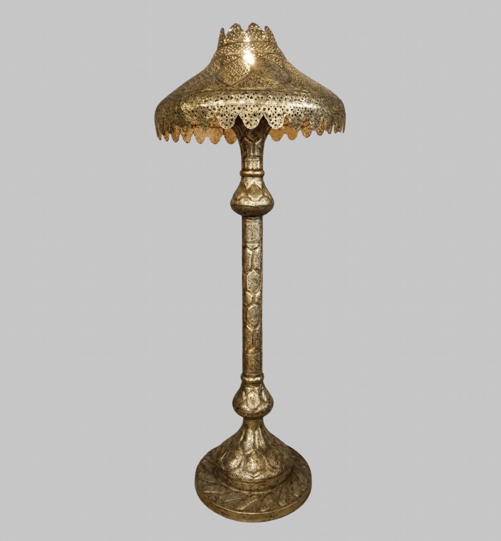 A tall Middle Eastern style brass floor lamp with an intricate pierced shade, decorative central column, and a wide flared base.