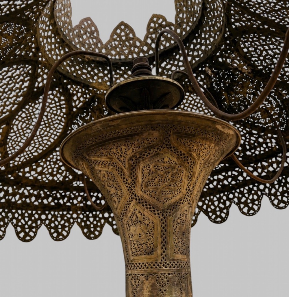 A tall Middle Eastern style brass floor lamp with an intricate pierced shade, decorative central column, and a wide flared base. View VII