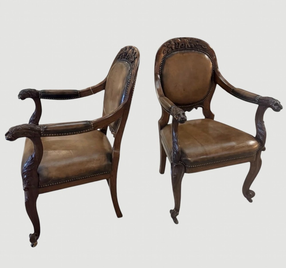 A pair of carved rosewood armchairs featuring dark leather upholstery, brass stud detailing, carved elephant crests, lion-head armrests, and cabriole legs. View III