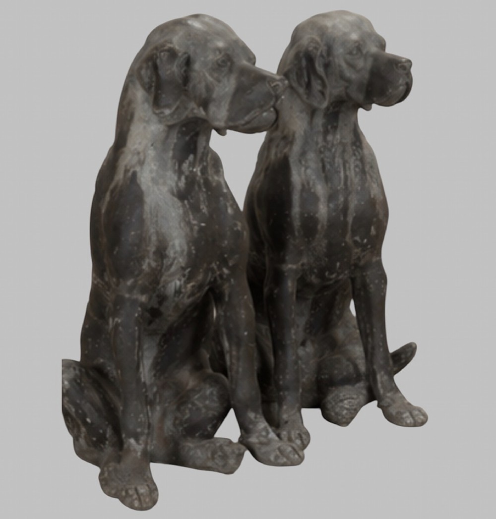 A pair of life-size cast lead sculptures depicting seated hounds with detailed anatomical features and a weathered grey surface. View III