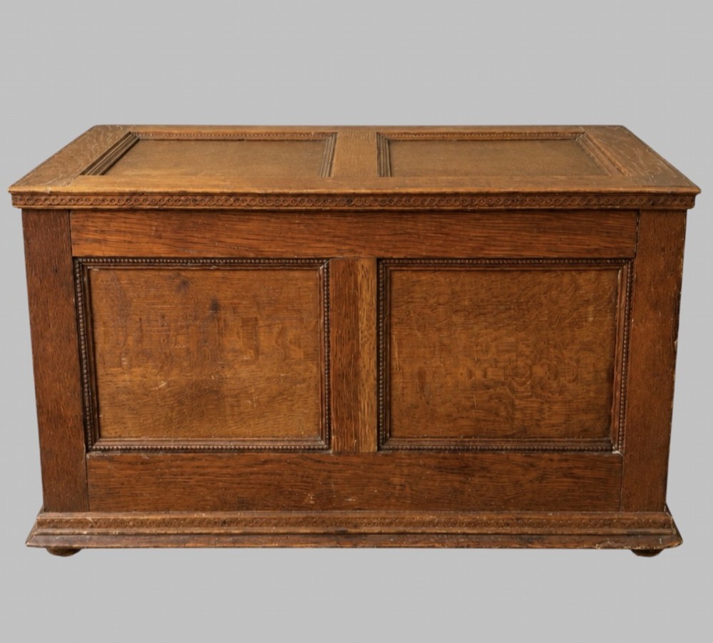 A solid oak Edwardian blanket chest featuring twin recessed front panels with carved beaded trim and a matching hinged lid.