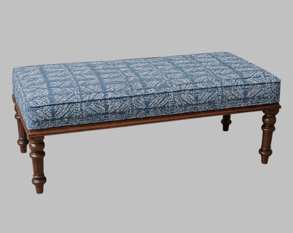 A rectangular late Victorian walnut window seat with turned wooden legs and a blue patterned upholstered cushion.