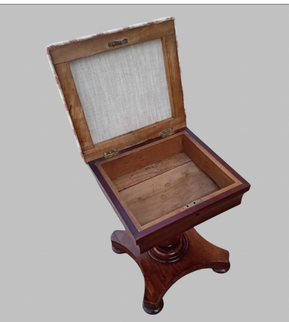 An upholstered William IV mahogany sewing box stool with red and cream striped fabric, mounted on a turned central pedestal and a concave platform base with bun feet. View II