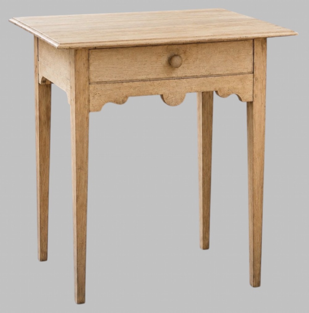 A mid-18th-century bleached oak side table featuring a single frieze drawer with a turned wooden knob, a shaped apron, and four square tapered legs.