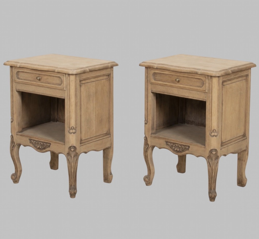 A pair of antique bleached oak bedside tables featuring carved cabriole legs, open storage shelves, and single top drawers with brass knobs.