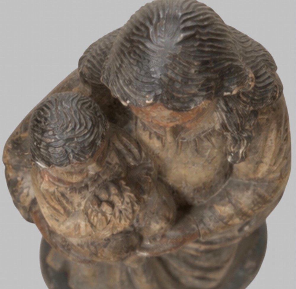 A carved wooden statue depicting the Virgin Mary holding the Infant Jesus on an integrated round base. View IV