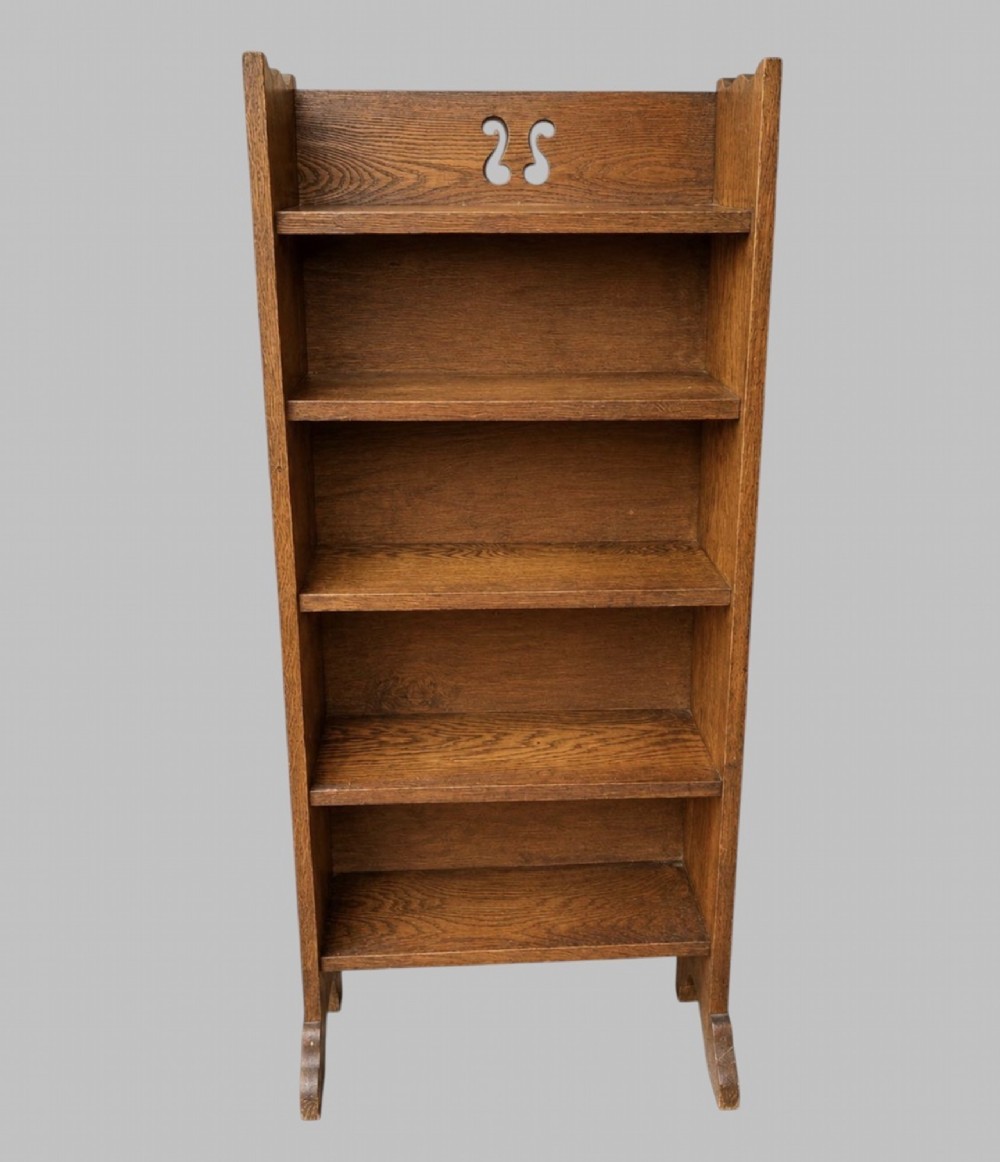 An early twentieth-century Arts and Crafts solid oak open bookcase featuring five shelves and a carved cut-out motif at the top.
